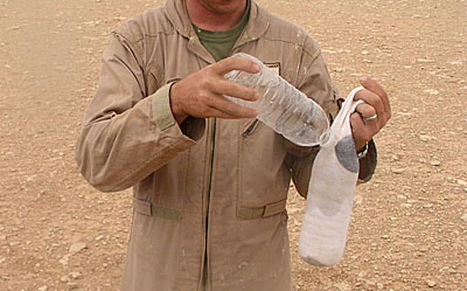 In the desert of western Anbar province, Marine Sgt. Michael Mills, 29, of Oceanside, Calif., slowly pours water on a bottle covered with a sock.