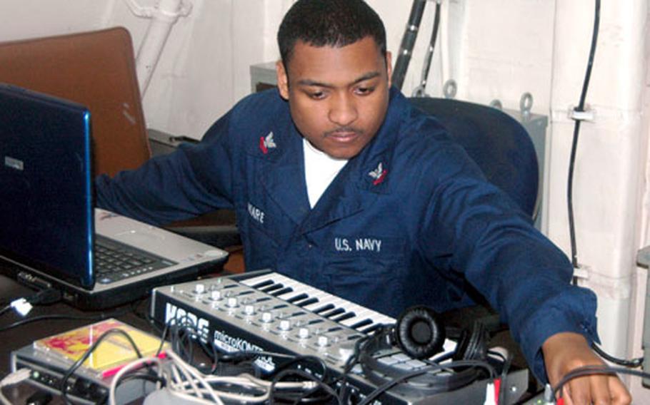 Petty Officer 2nd Class Frank Ware adjusts levels on a soundboard on his portable studio, working on his upcoming album aboard the USS Kitty Hawk.