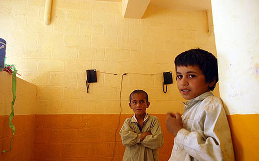 Two Afghan boys view the interior of a new telecommunications center that was opened recently in the village of Lash-e-Juwain.