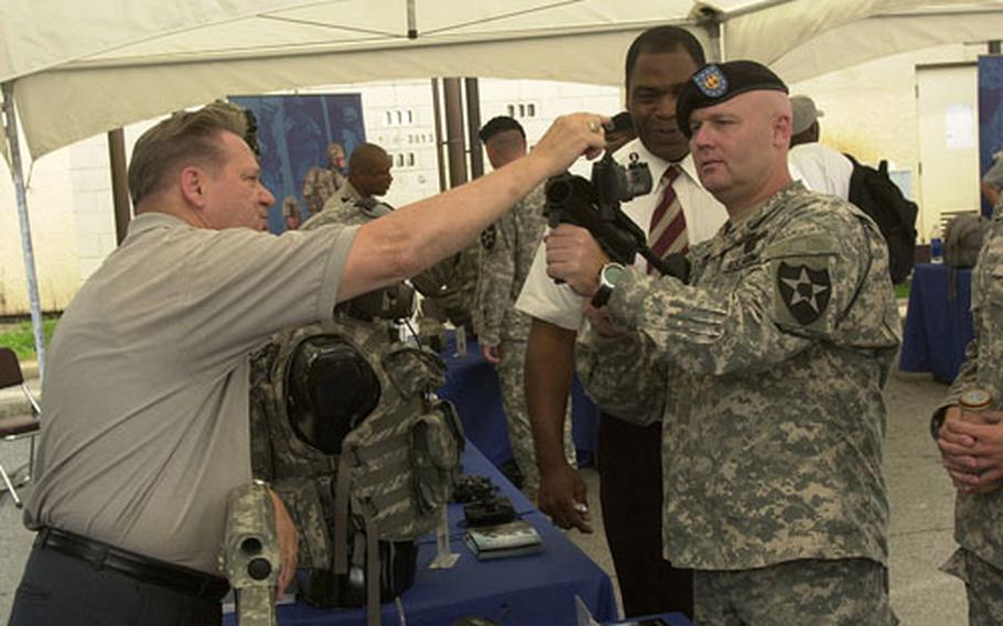 Ward Eldridge, left, shows a grenade launcher to Staff Sgt. Noel Harris, of Special Troops Battalion, 2nd Infantry Division at Camp Casey, South Korea. The Program Executive Office Soldier show during the past week gave soldiers throughout the peninsula a peek at the newest weapons, equipment and technology.