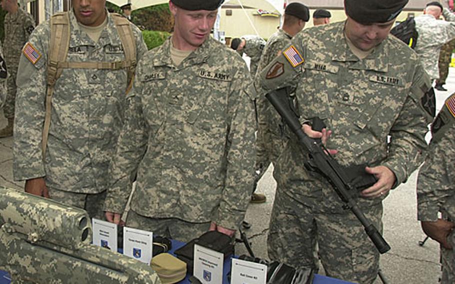From left, Pfc. Ivan Varela, Pvt. Benjamin Crumley and Sgt. 1st Class Aaron Weed look at new weapons, such as the one Weed is holding, an XM26 12-gauge shotgun. The shotgun is designed to attach to the M4 rifle.