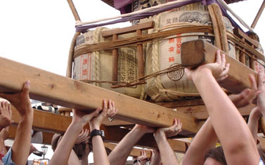 In Fussa City airmen from Yokota Air Base, Japan, lift a float called a mikoshi for the Tanabata celebration (Japanese Star Festival).