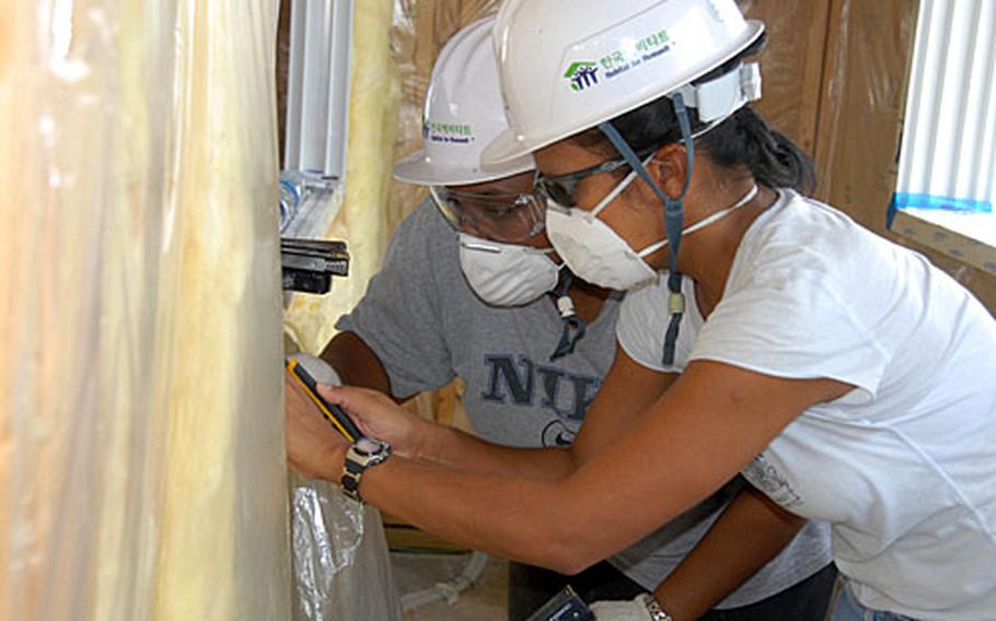 Staff Sgt. Menise Stakens, left, and Staff Sgt. Gracey Martinez help in building a housing complex for Habitat for Humanity. Nearly 140 airmen at Kunsan Air Base volunteered to build the complex, which will house eight South Korean families.