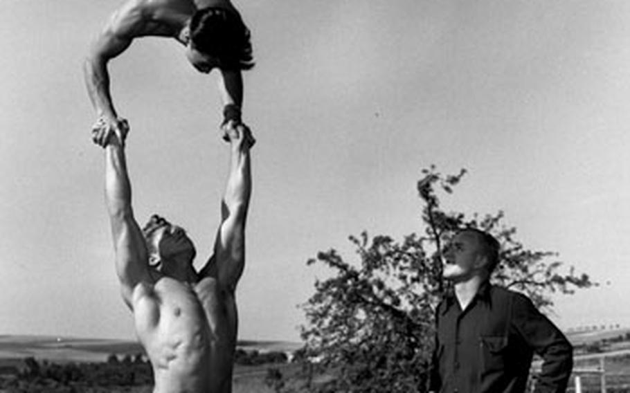 Tommy Kono gets a lift from Clyde Emerich as Jack Bluebaugh watches.