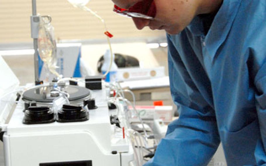 Senior Airman Robert Boles runs blood through a machine to remove the preservative, glycerol, making it usable for humans.