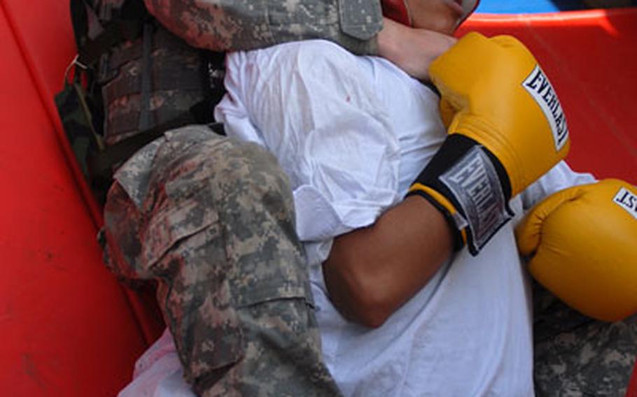 Southern European Task Force soldier of the year Spc. Ashly Flores (bottom) wrestles with a "detainee" during the U.S. Army Europe Soldier of the Year competition at Grafenwöhr, Germany.