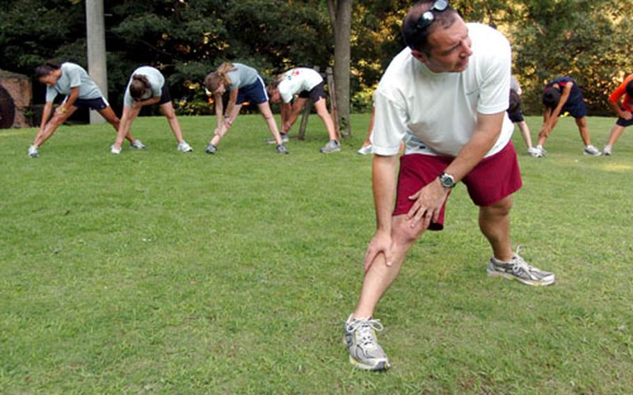 Beau Veazey, Yokota Middle School’s cross-country coach and the organizer for this week’s Kanto Plain Running Camp, heads up a stretching exercise for camp participants Wednesday at Tama Hills Recreation Area in Tokyo.