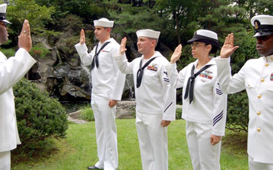 Chief Petty Officer Darius Wallace delivers the oath of enlistment to, from left, Petty Officer 3rd Class Robert Arroyos, Petty Officer 2nd Class Raymond Rizzo, Petty Officer 1st Class Laura Ozenne and Chief Petty Officer Franswya Talbert during a reenlistment ceremony Wednesday at the Dragon Hill Lodge, Yongsan Garrison, South Korea.