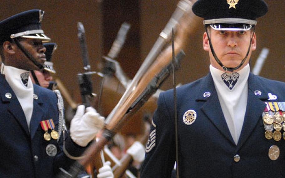 Master Sgt. Jacob Pullin, Air Force Honor Guard drill team flight chief, stands in front of airmen spinning rifles during a demonstration Aug, 2 at Spangdahlem Air Base in Germany.