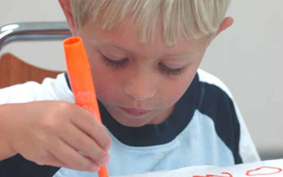 Connor Steele, 5, writes his name on a pillow case that he and his mother, Christine Steele, will mail to Connor's father, a sailor who is deployed to Kuwait until about February. Connor attended a workshop Monday in which experts gave coping tips to families of deploying sailors.