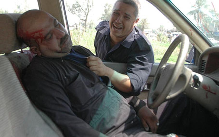 An unidentified colleague wails over the body of Iraqi policeman Rabee Ghazi, slumped in the driver's seat moments after he was killed by drive-by shooters. The colleague had been in the truck with Ghazi when the attack occurred in the Yarmouk area of central Baghdad.