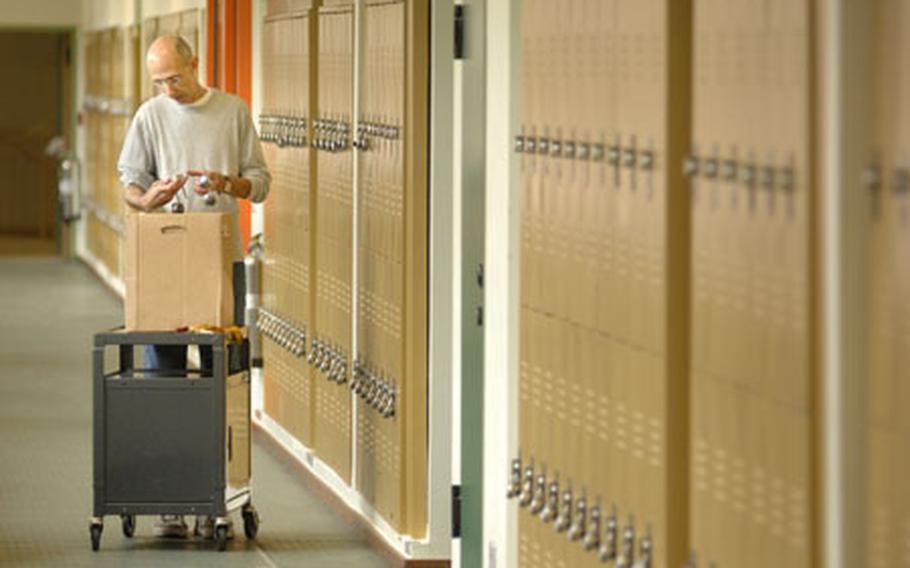 Charlie Harrell, a 7th grade geography teacher at Baumholder High School, matches locks to lockers Wednesday before students return to kick off a new school year.