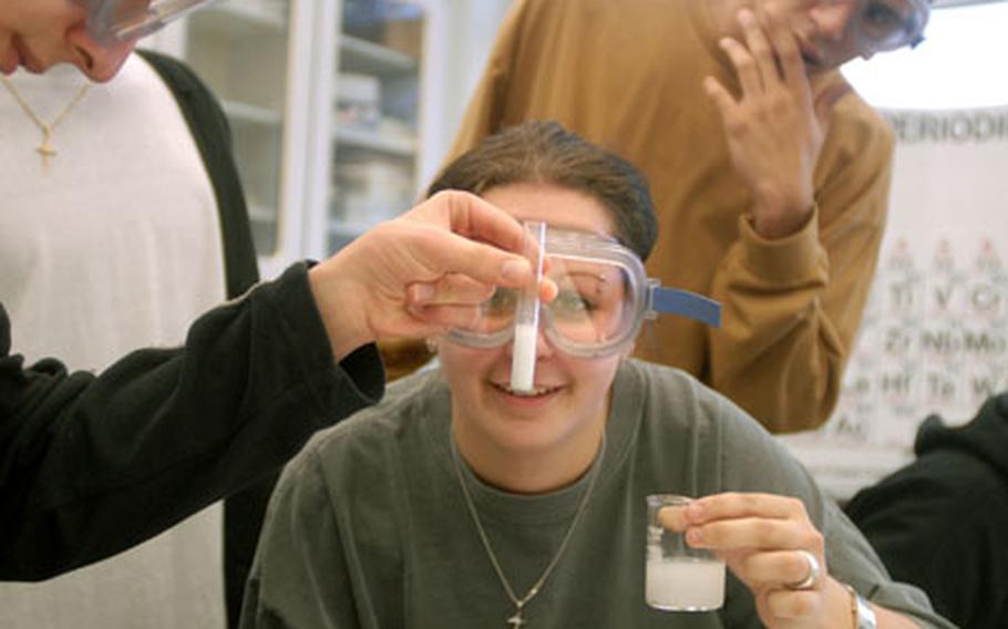 Nadine Sestan, an 11th grader at Kaiserslautern High School, watch as Lewis Robertson, also an 11th grader, holds a fizzling vile of magnesium oxide mixed with hydrogen peroxide during chemistry class March 14, 2007.