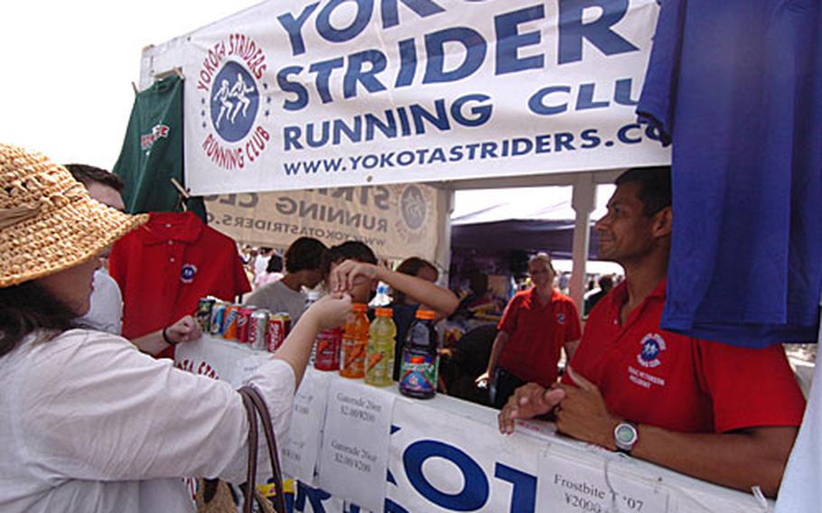 Amelia Arnold gives a customer change, while Master Sgt. Thomas Peterson, right, looks on in the Yokota Striders Club booth at the 57th annual Japanese-American Friendship Festival at Yokota Air Base, Japan. The club sold cold drinks, T-shirts and coins during the two-day event.