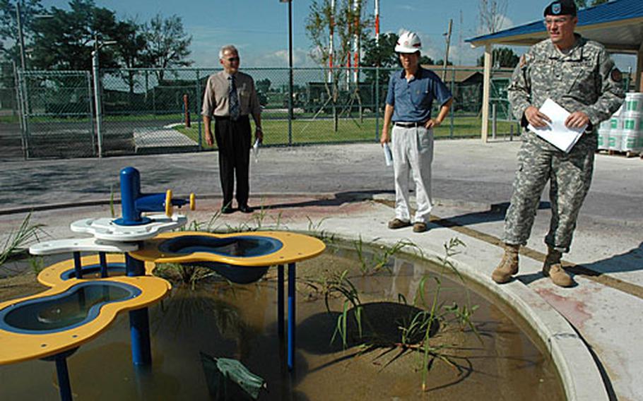 Col. John Dumoulin, right, the Camp Humphreys commander, looks over a final work project at the base’s new Bang Jung-Hwan Child Development Center with representatives of Samil Enterprise Co., the construction firm that built the center. This outdoor sand area has a drainage problem, which the construction company must fix.
