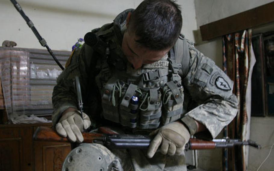 Spc. Wesley Russell, 20, of Birmingham, Ala., marks the grid coordinate of the house in which an AK-47 rifle was found during a raid targeting Sunni insurgents in the village of Adiwaniyah, about 15 kilometers south of Baghdad's Green Zone.