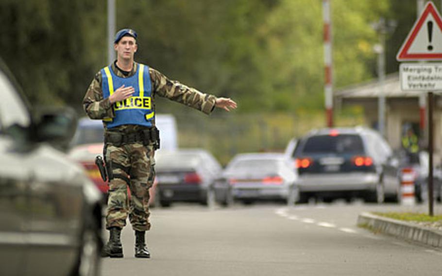 Peter Beutler, a civilian security guard from the 435th Security Forces Squadron, directs a car for random inspection Wednesday at Ramstein Air Base’s West Gate.