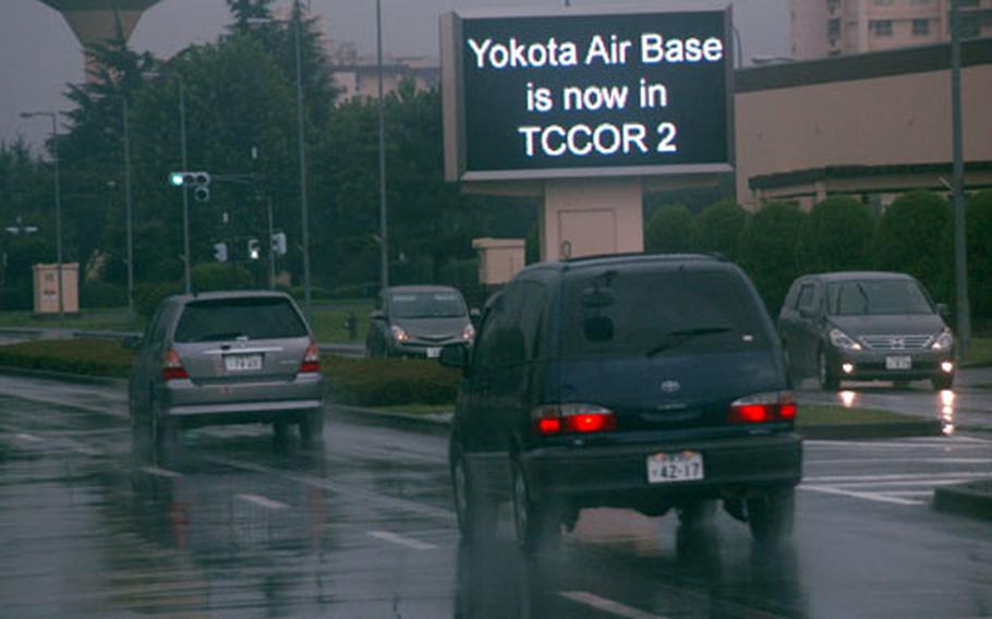 As rain falls Wednesday afternoon at Yokota Air Base, Japan, the video marquee on Airlift Avenue announces the latest Tropical Cyclone Condition of Readiness alert to passing motorists.