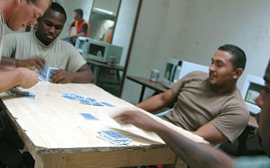Troops from the 1st Cavalry Division play cards to help fill the time void at Combat Outpost Hope near Baghdad's Sadr City.