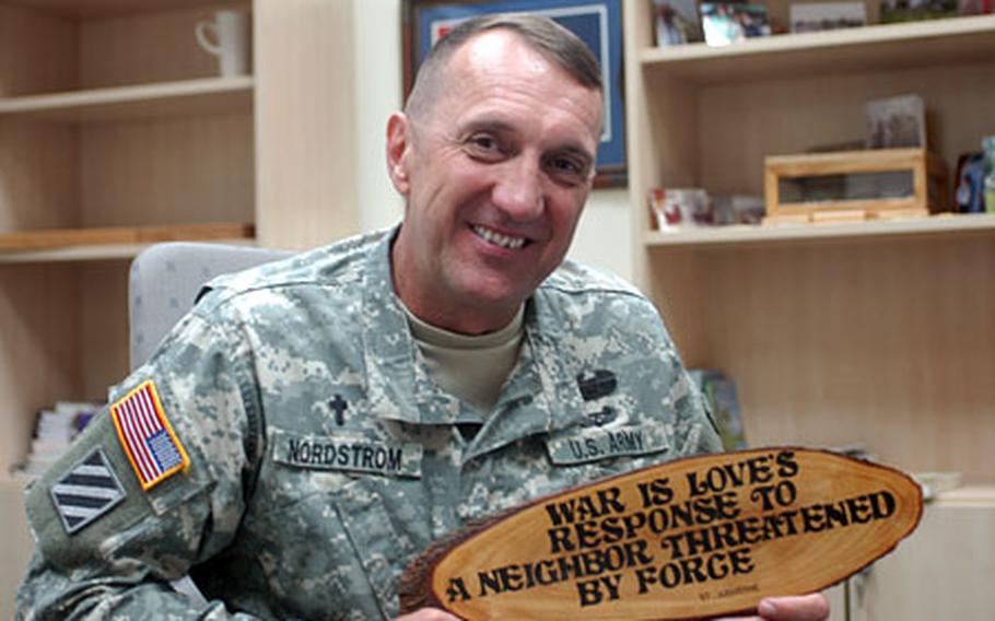 Chaplain (Maj. ) Mark Nordstrom, who has a Mennonite background, holds a plaque given to him by another chaplain in Baghdad. The quote is from St. Augustine, who devised a theory of the "just war." Most Mennonites, however, say Christ teaches peace and non-violence and that participation in the "war machine" is wrong.