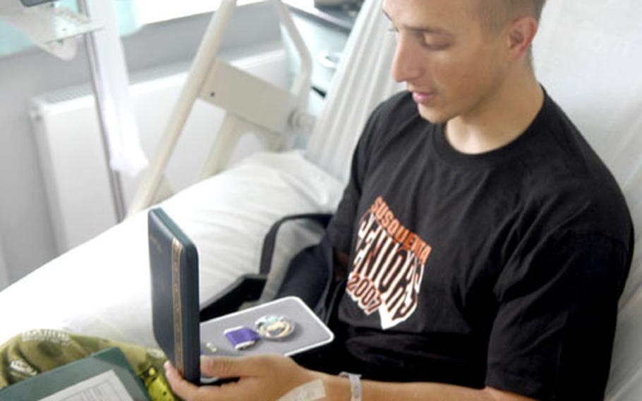 Pfc. Gregory Simms was presented with the Purple Heart on Friday while recuperating at Landstuhl Regional Medical Center in Germany.