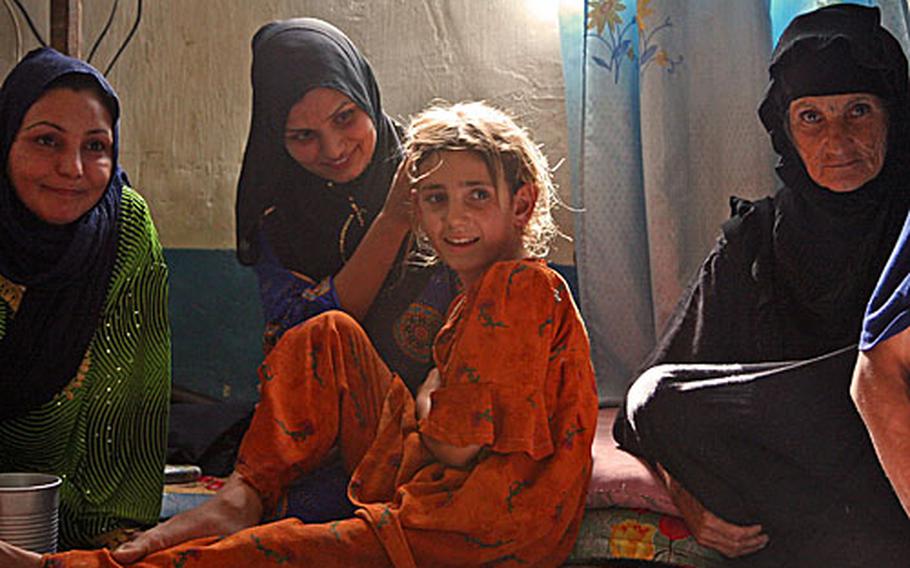 Suham Hassan Ka-Naan touches her niece's hair as a translator relays a question during an interview Sunday at their home southeast of Baghdad. Suham lost her legs during an insurgent mortar attack three years ago. Her sister (left), Hayat, was born crippled, and their niece was hit by a truck, leaving her with a severe limp.