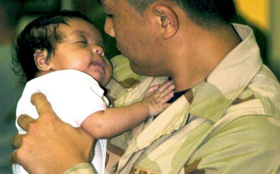 Senior Airman Vivo Jorley holds his month old daughter Jayla in the Air Mobile Command Terminal. Airmen from the 374th Airlift Wing gather in the Air Mobile Command Terminal on Yokota Air Base, Japan on Saturday. He deployed with roughly 80 airmen in support of Operation Iraqi Freedom and Operation Enduring Freedom.
