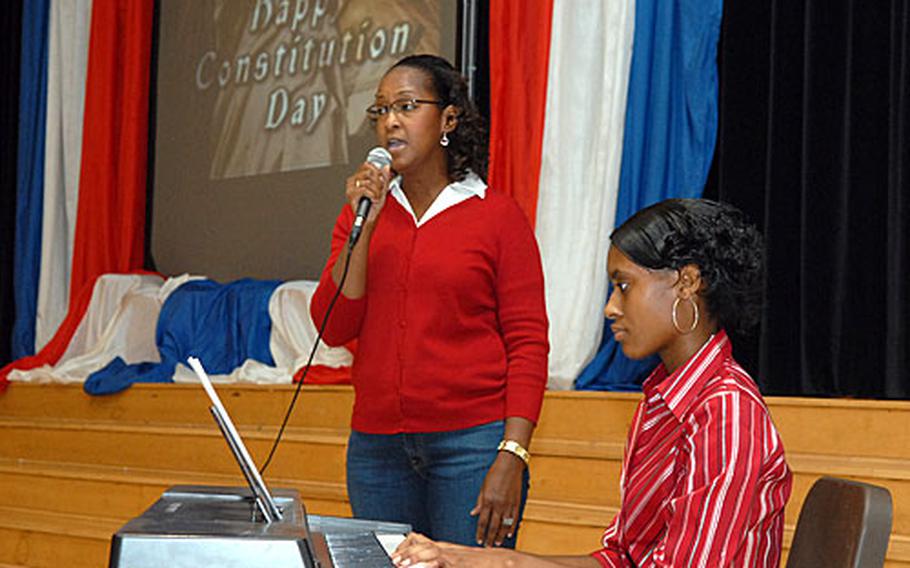 Leisa Santiago Boetler, left, of the school bus office, sings "My Country 'Tis of Thee" accompanied by junior Roberautrice Eddie on keyboards, at the Hanau Middle/High School Constitution Day ceremony.