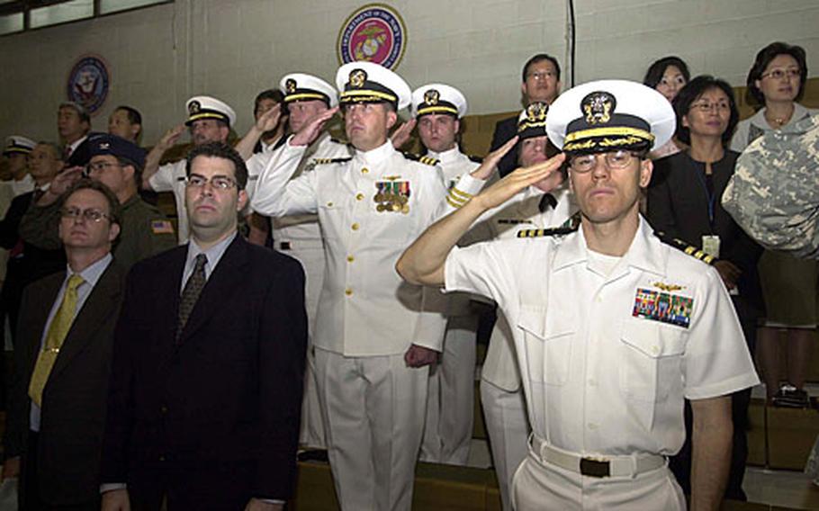 Military members salute during the singing of the National Anthem during the U.S. Naval Forces Korea change of command ceremony on at Yongsan Garrison.