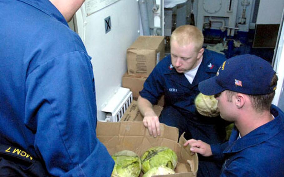USS Patriot crew members sort cabbages Wednesday in preparation for the ship's departure, Thursday, on a several-month fall patrol. From left to right, they are Seaman Recruit Michael Kizer, Petty Officer 2nd Class Dennis Oerly and Seaman Apprentice Kyle Ames.
