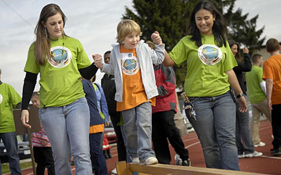 Airman Amanda Frederick and Airman 1st Class Charline Breal, both volunteers from the 52nd Security Forces Squadron, help Johanna Koch, 6, across the balance beam Thursday during the St. Martin’s Special Children’s Day held at Spangdahlem Air Base, Germany. Over 70 kids from St. Martin’s teamed up with volunteers to play games, eat American style food and have fun just plain fun at the base fitness center.