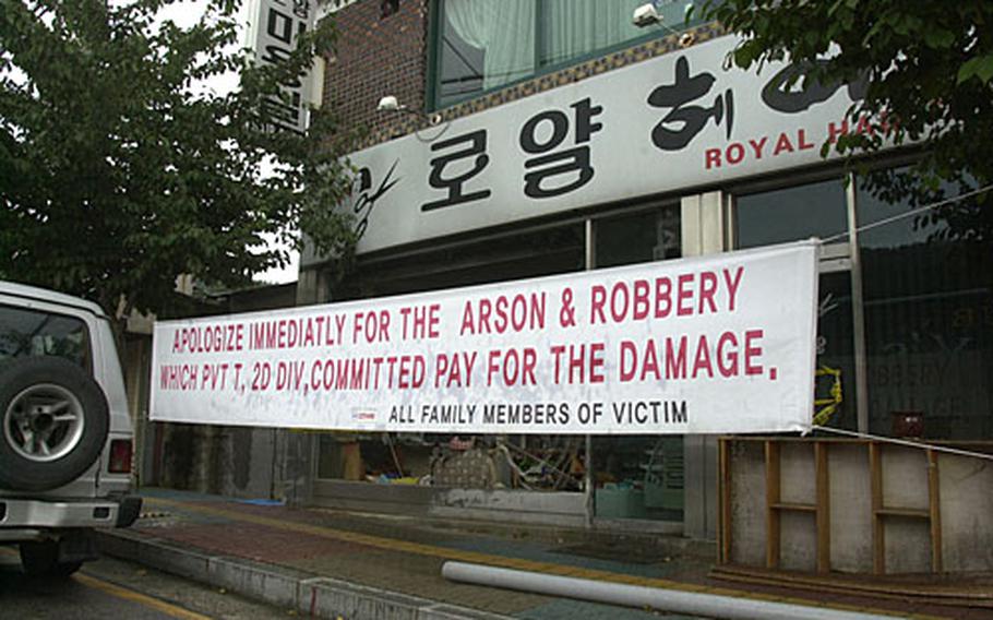 A banner outside the Royal beauty shop near Camp Hovey’s gate in Dongducheon seeks compensation for a May 19 fire that some say was started by a U.S. soldier.