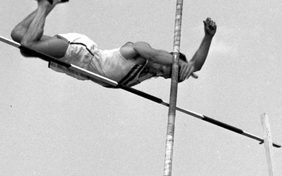 Dick Morcom clears the bar in the pole vault.