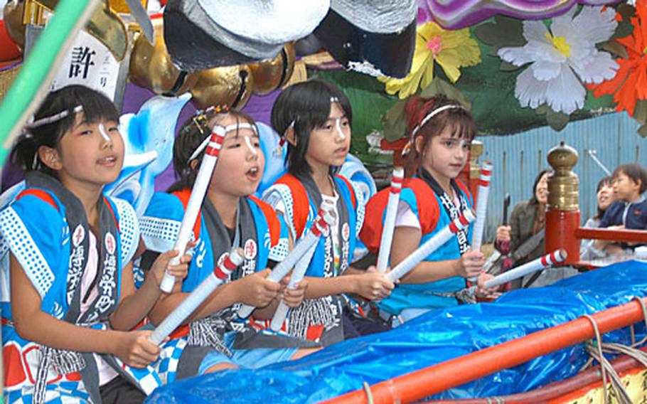 Emily Reams, 8, far right, plays the taiko drums while sitting on a parade float during a festival Sept. 2 in the northern Japan town of Gonohe. Reams, whose parents work on Misawa Air Base, was the only American playing taiko in the festival. Reams has attended Japanese school since the age of 3 and is fluent in the language.