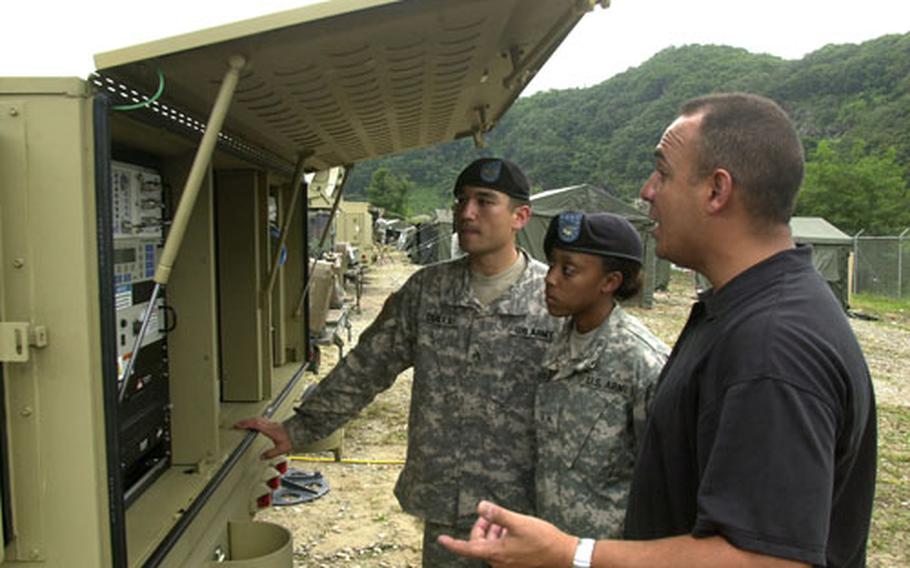 Contractor Kevin Cruz of Datapath, right, talks with Sgt. Peter Scales and Pvt. Jessica Hutchins of 4th Battalion, 2nd Attack Aviation, about the new system for field communication at Camp Hovey.