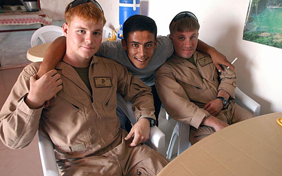 Col. Marshall Terrin, 20, of Las Vegas and Cpl. Benjamin Horlander, 26, of Tyler, Texas, hang with one of the workers at a Hamdiyah restaurant popular with U.S. servicemembers based in Camp Blue Diamond.
