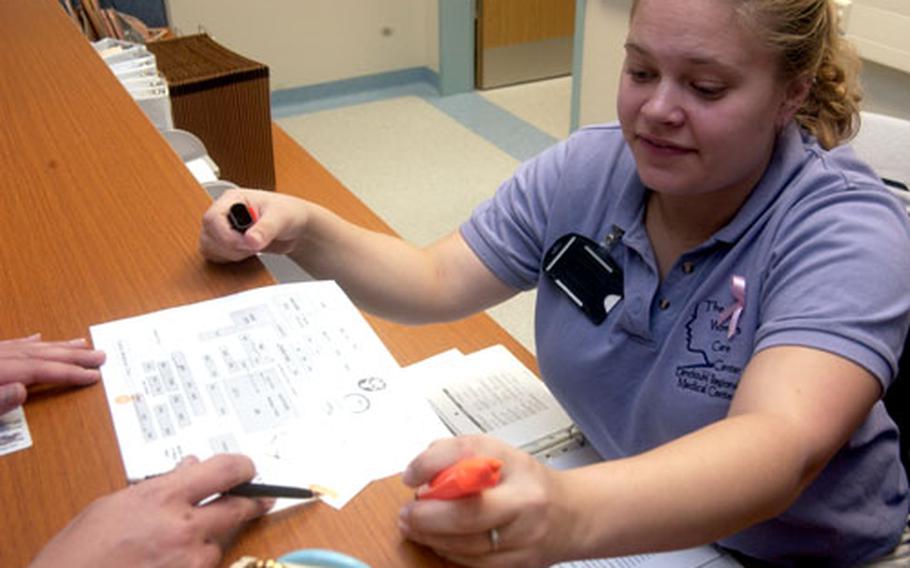 Terianne Edwards, a medical support assistant at Landstuhl Regional Medical Center&#39;s Women&#39;s Care Center, helps a patient.