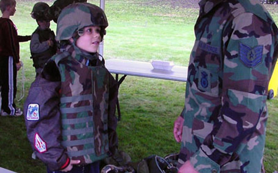 Tech Sgt. Terrance Winds introduces several pieces of gear to Croughton Elementary fourth-grader Adam Davis during the Camp KUDOS program. The program offers Air Force kids a chance to see what their parent's deployments are like.
