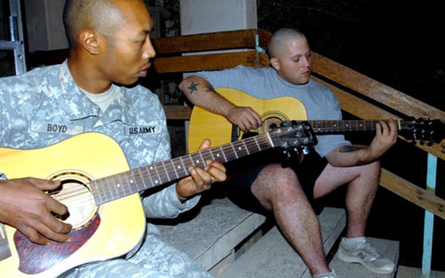 Spc. Gary Boyd, 24, of Morrow, Ga., left, and Pfc. Ivy Harris, 21, of Adairsville, Ga. play guitar on the front steps at Combat Outpost Aztec, Baghdad, Iraq on Tuesday.