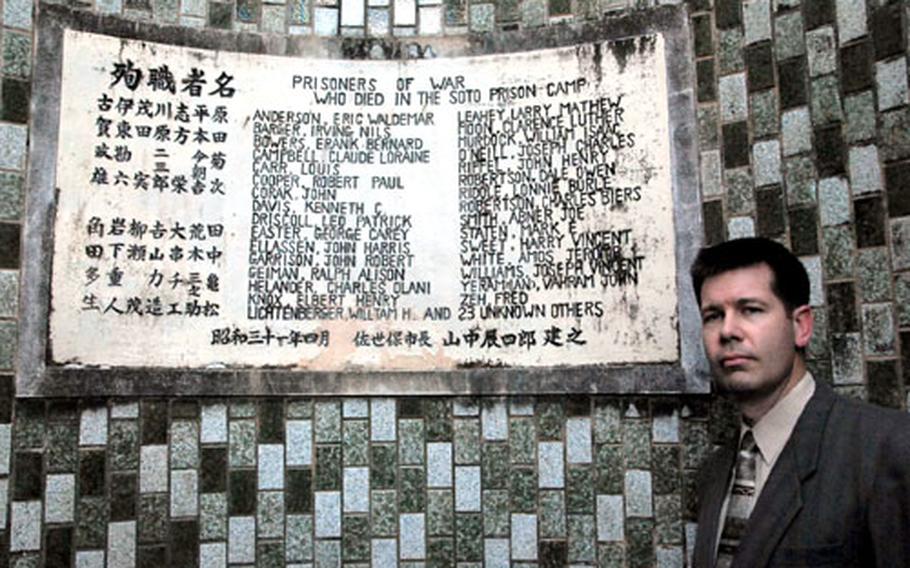 Amateur historian Phil Eakins stands beside the Soto Dam memorial plaque, which lists names of American prisoners who died building the dam. Eakins says his research has uncovered many new names of casualties and proves that many names listed on the plaque are incorrect.