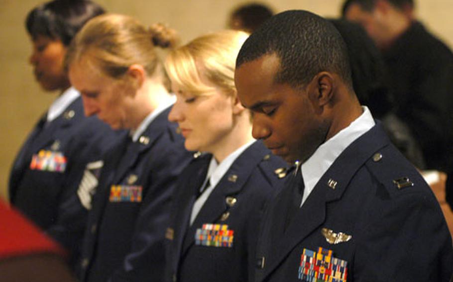 Airmen bow their heads in prayer.