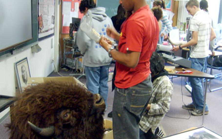 Jackson Knox, a senior at Ramstein High School, examines an American Indian tool and buffalo head during Peter Heiser’s talk on American Indian culture and history on Wednesday.