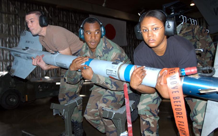Airman 1st Class Jolin Daigneault, Staff Sgt. Emmett Cornelius, and Senior Airman Takiyah Prince, left to right, work together to lift a missile to be loaded on an F-16. The three are weapons loaders with the 13th Aircraft Maintenance Unit and competed Friday for bragging rights as the best weapons loaders at Misawa Air Base.