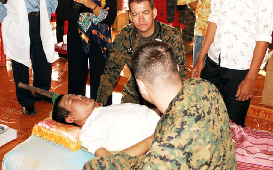 Lt. Todd E. Gregory, a surgeon with the Okinawa-based 31st Marine Expeditionary Unit, and Lt. Lance R. Henninger, an air combat element flight surgeon, examine a patient during a medical and dental aid project recently in Kampong Cham, Cambodia. The sailors and the Okinawa-based 31st Marine Expeditionary Unit spent Nov. 26-29 providing the health care aid.
