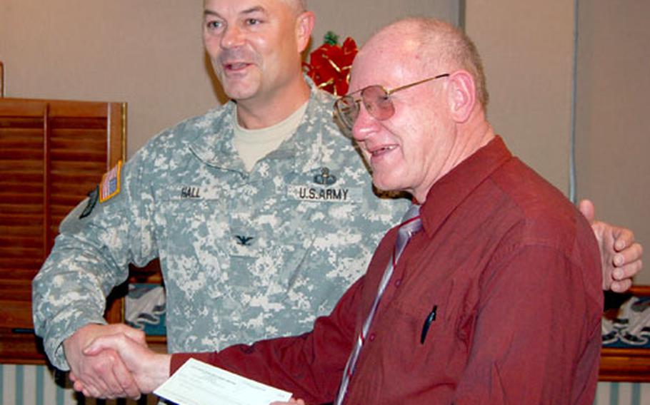 Yongsan Garrison commander Col. Dave Hall presents Shalom House director Bill Meyers with a check for $19,733.87. The money — gathered from military chapel collection plates — will be used to support Raphael Clinic, a Catholic organization that provides free medical care to third-country nationals.