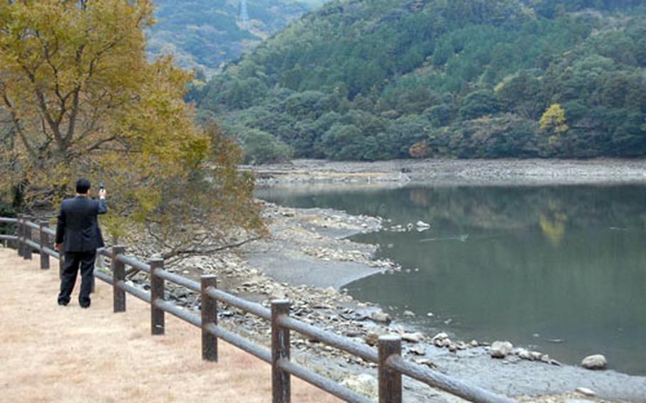 A man snaps a photograph of Sasebo city's most depleted reservoir, Yamanota, which was more than half empty Thursday. Sasebo Naval Base said it will begin rationing water on Dec. 17 to help conserve what is left of the city supply.