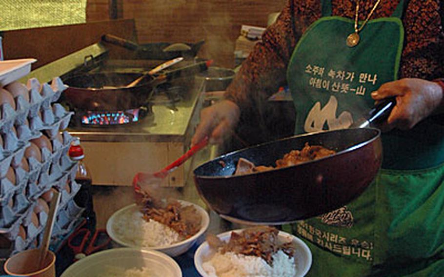 Lee Gi-nam serves up four bowls of bulgogi and rice just before noon. Lee says she and her sister have been cooking for U.S. troops training in the field in South Korea for 40 years.