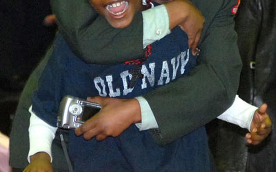 Iesha Reeves, a member of the Hanau High School JROTC, hugs her brother Jonathan Smith, after spotting their dad, Sgt. Jonathan Smith, marching into the Pioneer Casern gym.