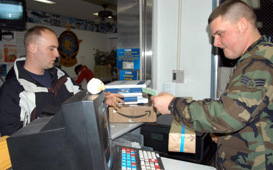 Senior Airman Matt Nyulassie, right, a postal clerk at the Misawa Air Base, Japan, post office, stamps and rings up mail for Tech. Sgt. Jason Peters on Thursday.