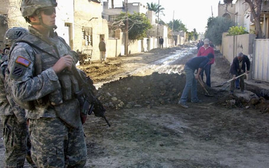Locals in Baghdad's Adhamiyah district repair roads Monday ruined by damaged sewer lines, while soldiers from Troop C, 3rd Squadron, 7th Cavalry patrol. The now all-Sunni district has been walled off from neighboring Shiite areas, including Sadr City about two miles north.